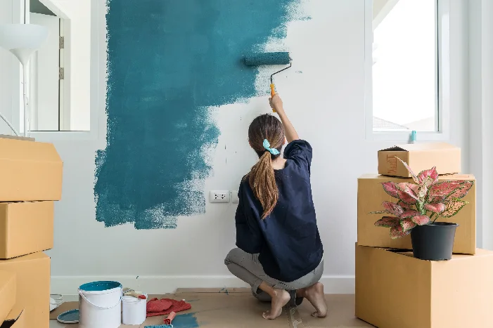 Person streicht Wand mit Farbrolle.